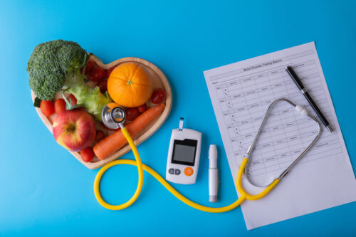 vegetable bowl in a heart shape with a stethoscope and a diabetes device and chart